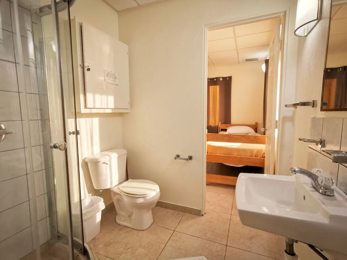 Un baño con inodoro y lavabo, con una habitación visible por la puerta