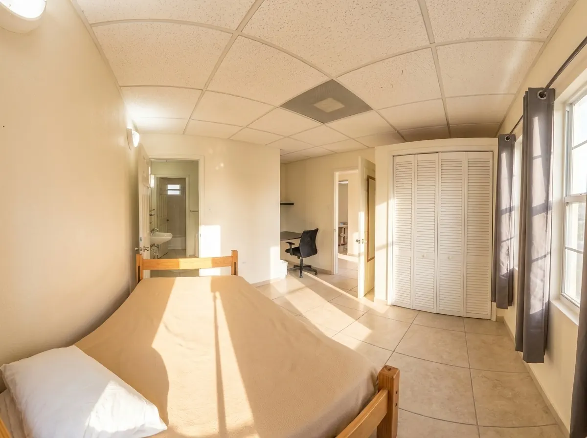 Una habitación privada con cama individual, armario y un escritorio bajo la ventana