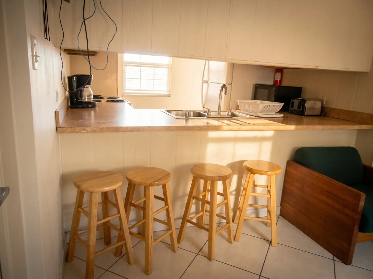 Un mostrador de cocina con bancos, fregadero, cafetera y tostadora