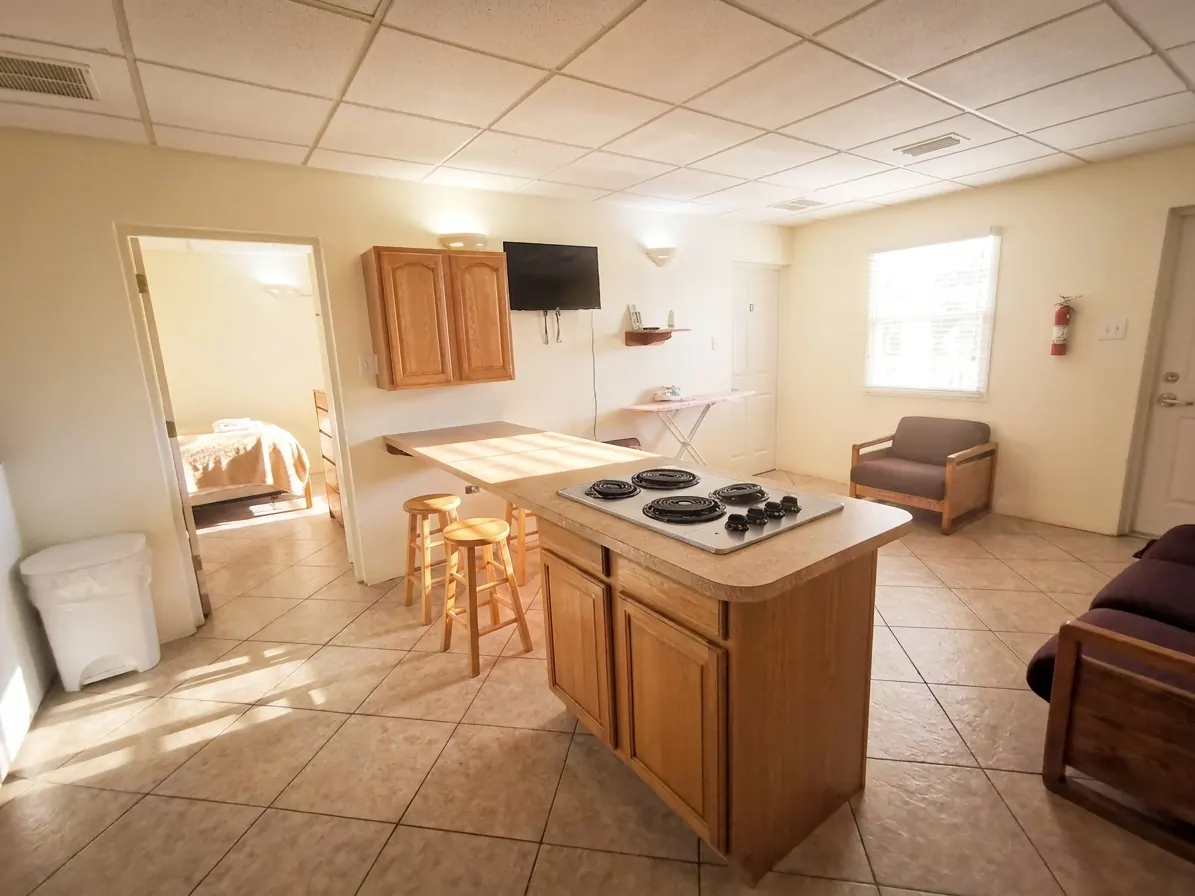 Una cocina y sala compartidas con estufa en la isla y asientos al fondo
