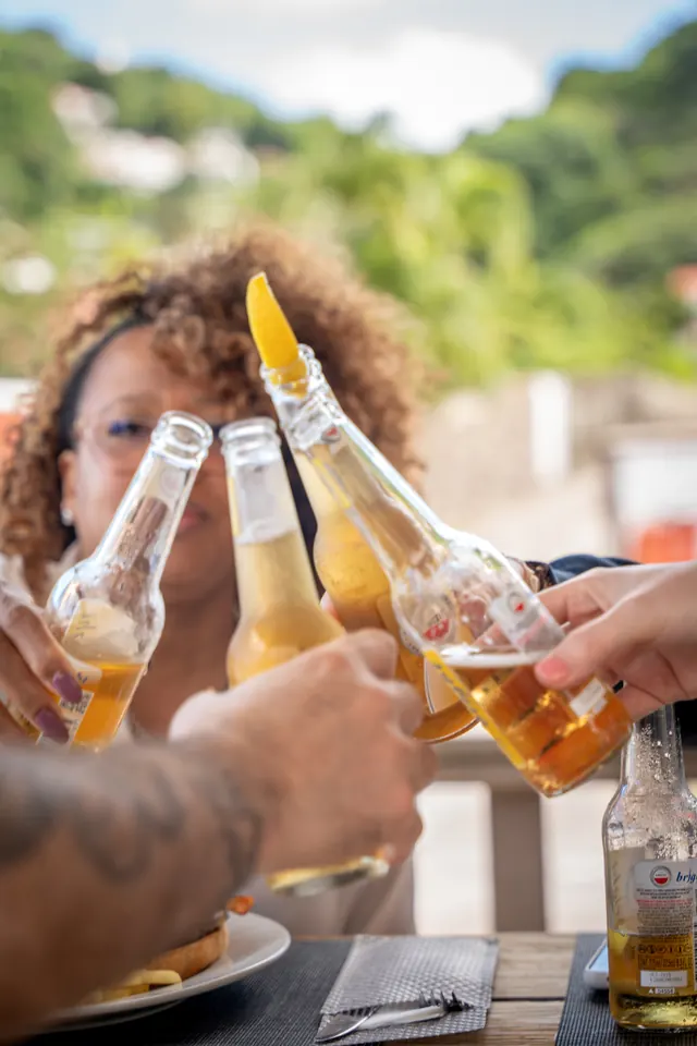 Three people touching bottles together at a bar on Saba