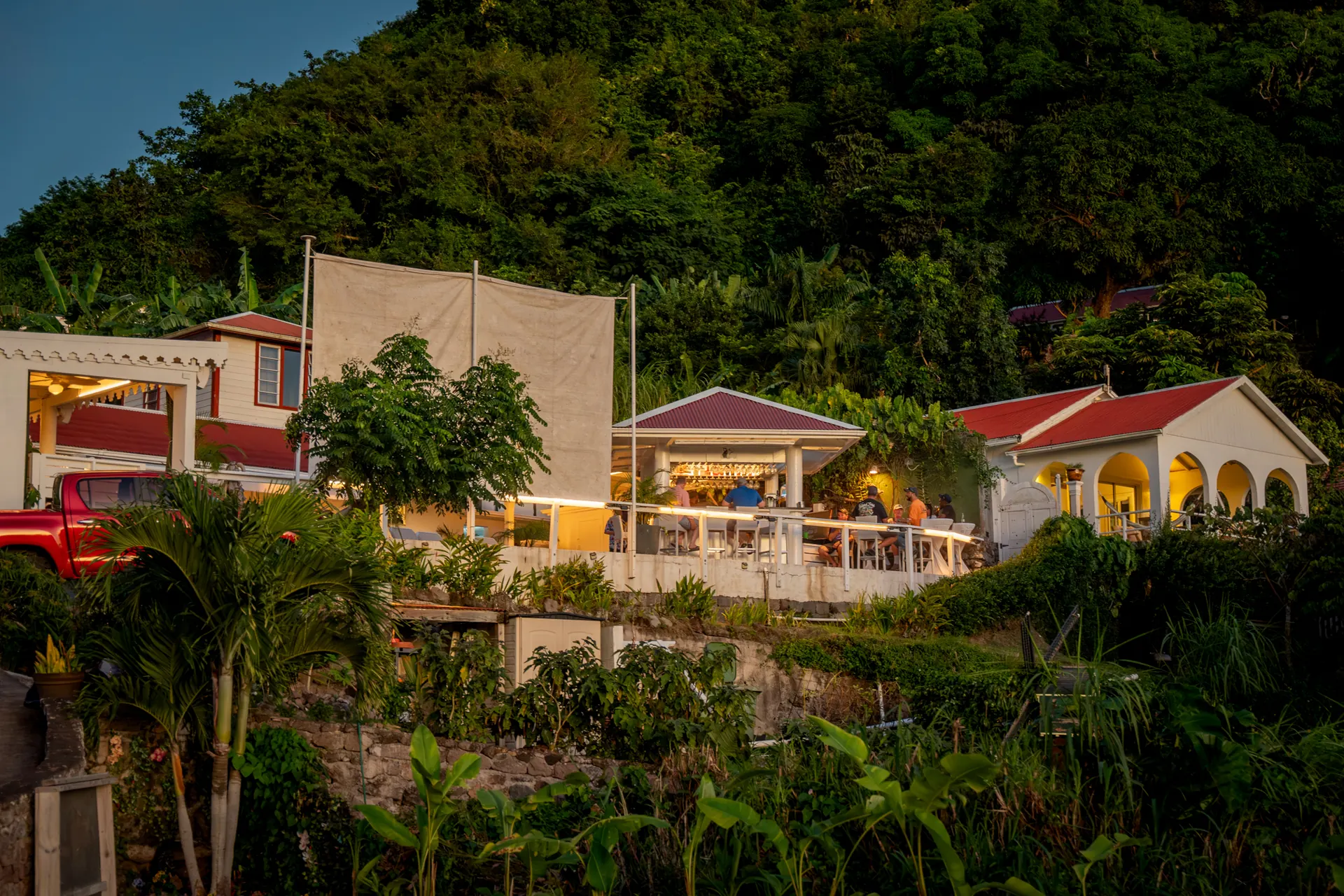 Casitas blancas de techos rojos en una ladera verde y empinada sobre el mar